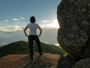 Rear view of man standing on rock looking at mountains