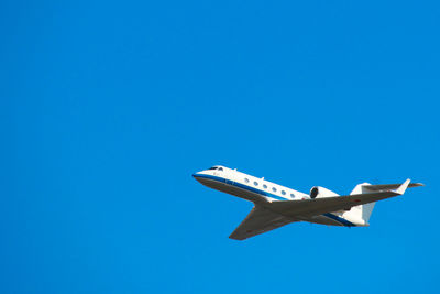 Low angle view of airplane flying against clear blue sky