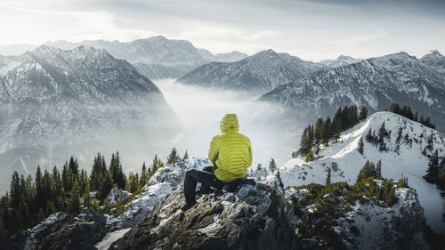 Rear view of person on snowcapped mountain against sky