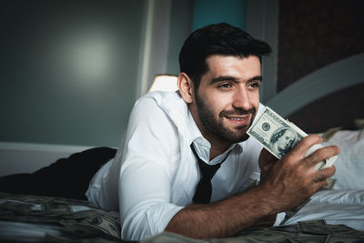 Portrait of a smiling young man sitting on bed