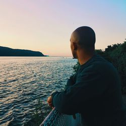 Man looking at sea against clear sky during sunset