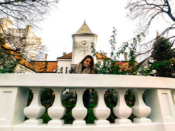 Portrait of young woman standing on built structure against sky