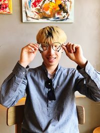 Portrait of smiling man looking through eyeglasses at home