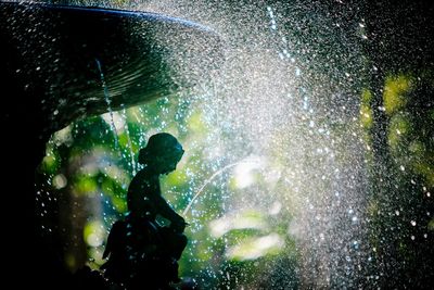 Silhouette man splashing water in rain