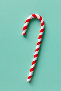 Christmas peppermint candy cane on pastel turquoise background. festive minimal style flat lay.