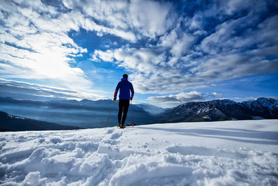 Rear view of man on snowcapped mountain against sky