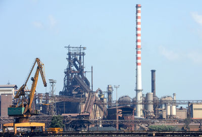Cranes in factory against sky