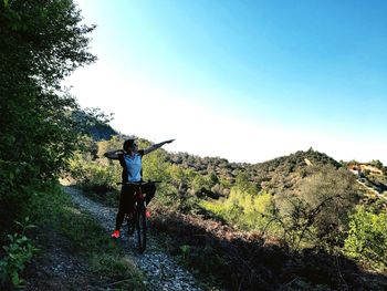 Man riding bicycle on street against sky