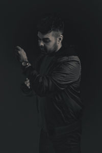 Young man standing against black background