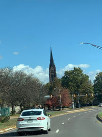 Cars on road by buildings against sky