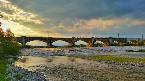 Bridge over river against cloudy sky