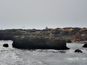 Rock formation in sea against clear sky