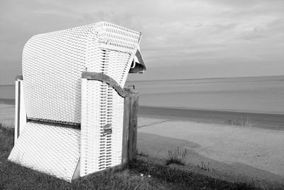 Hooded beach chair on sea shore against sky