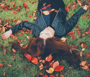 High angle view of woman lying on leaves covered field during autumn