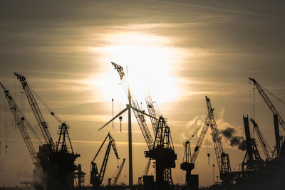 Cranes against sky during sunset