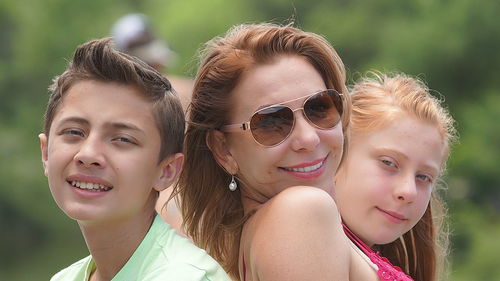 Close-up portrait of smiling mother with son and daughter outdoors