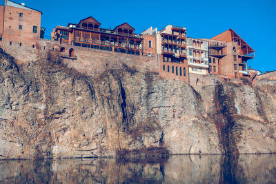 Buildings and rocks against clear blue sky