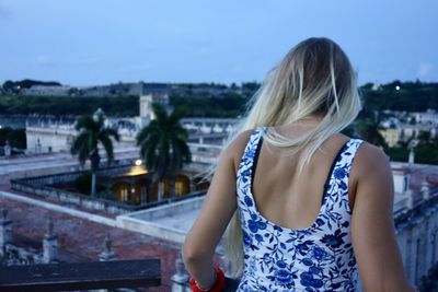 Rear view of woman standing in city against sky