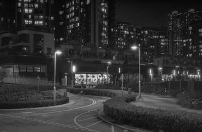 Illuminated street amidst buildings in city at night