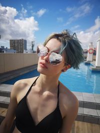 Woman wearing sunglasses against swimming pool