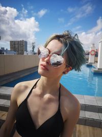 Portrait of woman wearing sunglasses against swimming pool