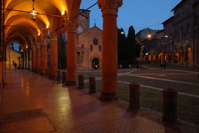 Illuminated street amidst buildings in city at night