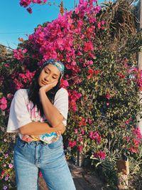 Portrait of young woman standing against plants