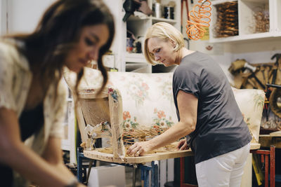 Female coworkers making furniture in upholstery workshop