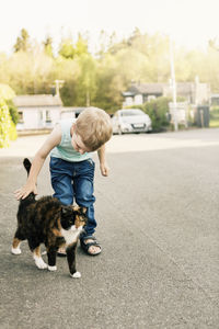 Son playing with cat on street