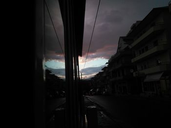 Cars on city street against sky during sunset