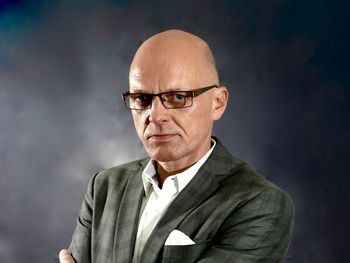 Portrait of serious mature man wearing eyeglasses while standing against wall