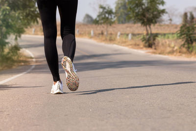 Low section of woman walking on road