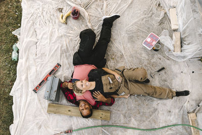 High angle view of smiling woman resting on partner after renovating during summer