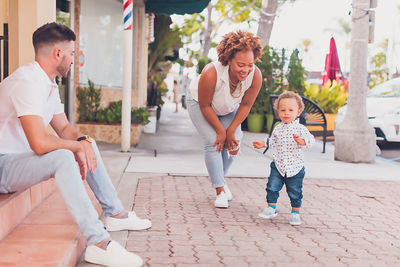 Interracial family playing with toddler on the sidewalk