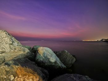 Rocks by sea against sky during sunset