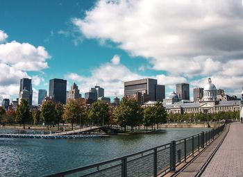 City by river and buildings against sky