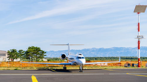 Airplane at airport runway against sky
