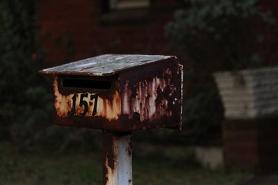 Close-up of old rusty mailbox structure on field