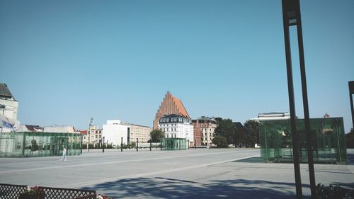 Street by buildings against clear blue sky