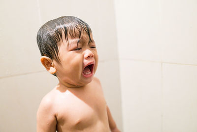 Portrait of shirtless boy in bathroom