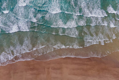 Aerial drone view of the waves on the sand beach