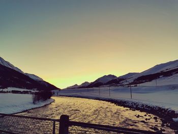 Scenic view of lake by mountains against sky during sunset