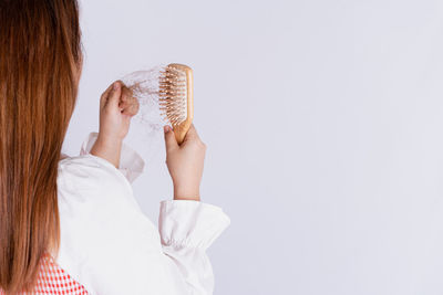 Rear view of woman holding ice cream against white background