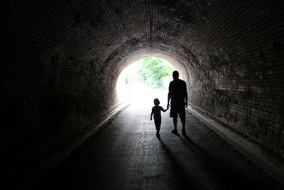 Silhouette man with child below tunnel