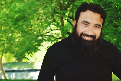 Portrait of smiling bearded man against tree