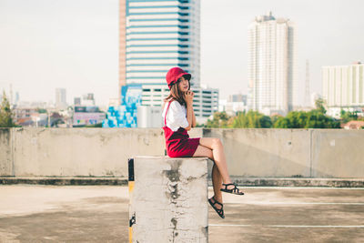 Side view of woman sitting against cityscape