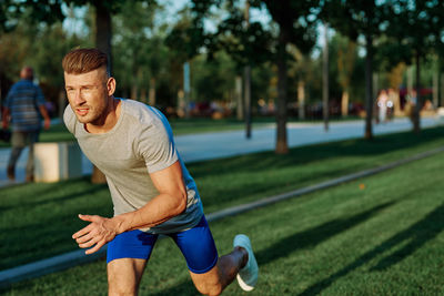 Portrait of young man exercising on field