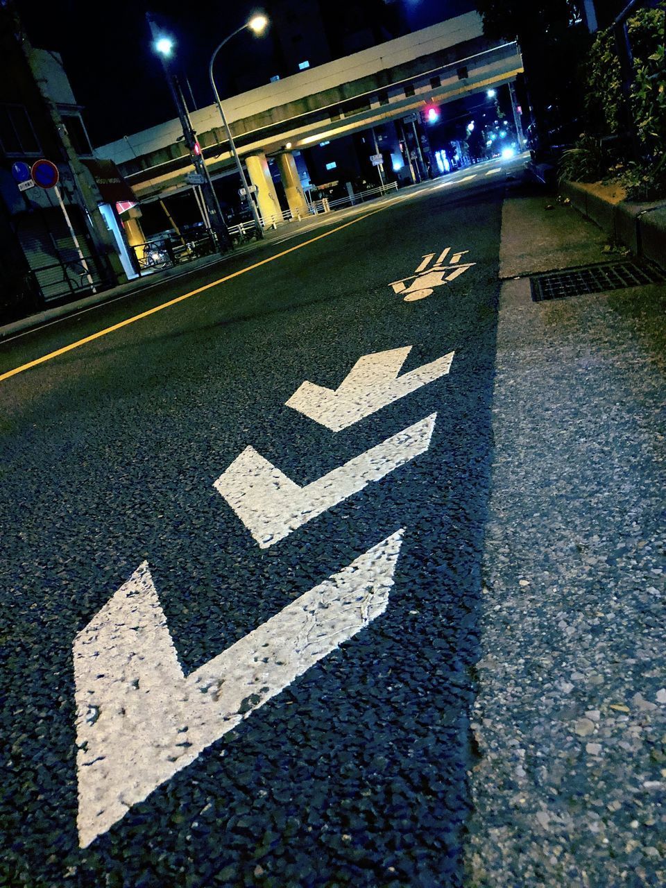 HIGH ANGLE VIEW OF ARROW SYMBOL ON ROAD IN CITY