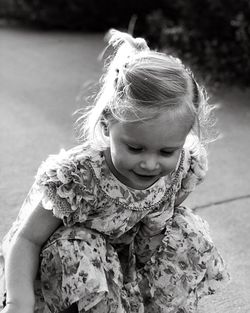 Close-up of smiling cute girl crouching on footpath