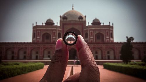 Midsection of man against built structure against clear sky